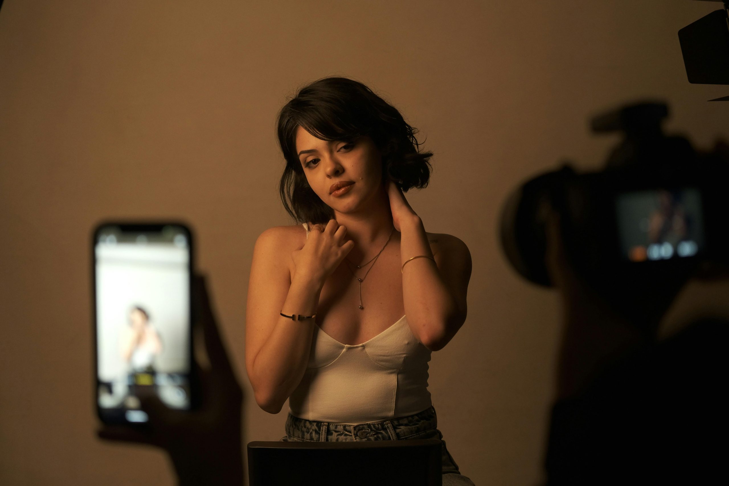Young woman posing in a studio during a photography session with cameras.